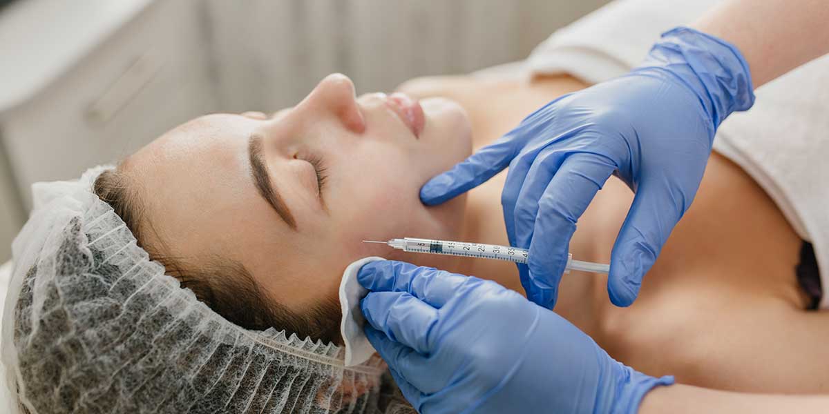 Young woman receiving a precise facial Botox injection treatment from a skilled practitioner wearing protective blue medical gloves.
